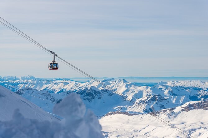 A red and silver cable car cabin crossing high above a white snowfield