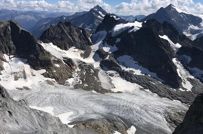 A crevassed glacier spreading below dark, jagged rock peaks