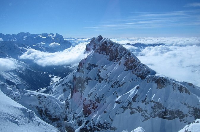 A snow-streaked rock ridge rising out of a sea of cloud in the valleys