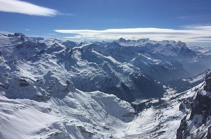 Snow-covered ranges stretching to the horizon under a pale sky