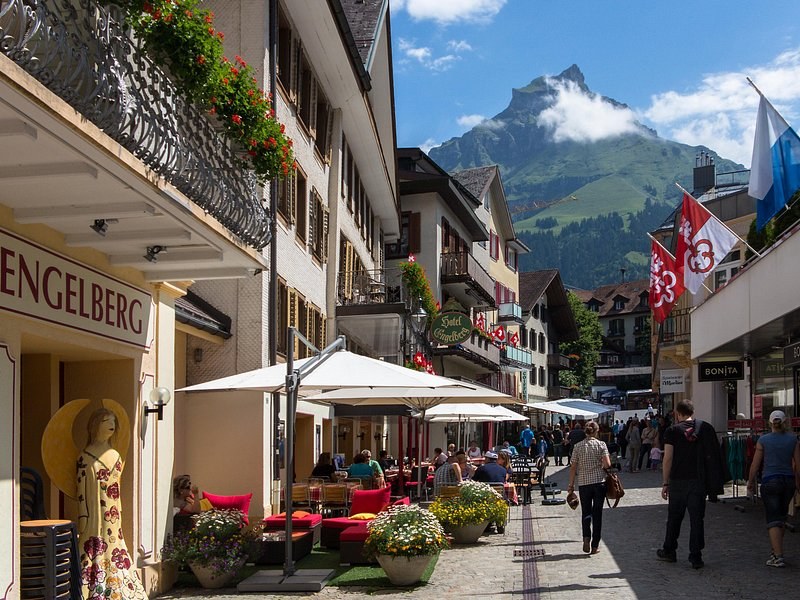 A village street of hotels and cafe umbrellas with a pointed peak behind